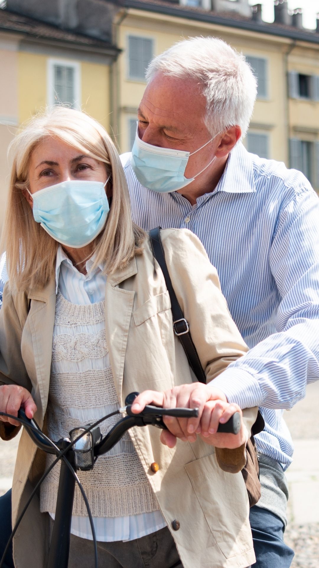 elderly couple with masks on an ebike